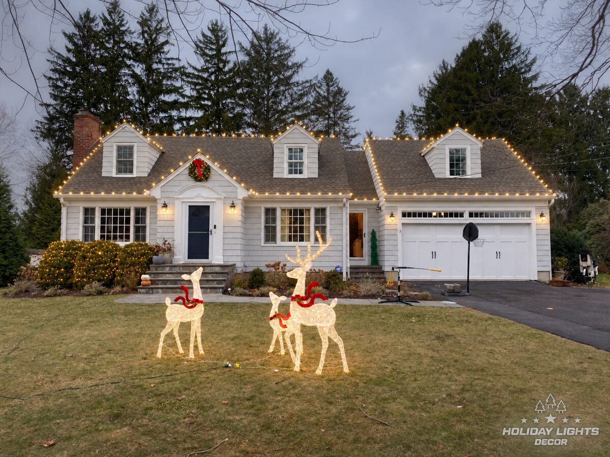 Warm white C9 lights on the dormers, entry gable and garage of a Cape Cod home in Easton, CT, lit wreath over the door
